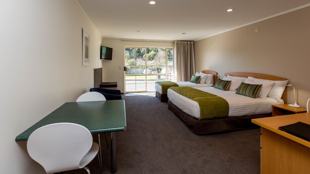 A hotel room with a bed, two bedside tables, a desk, a chair, and a television on the wall. - Aspen Court Motel Taihape (Taihape)