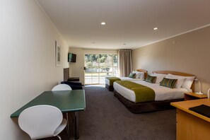 A hotel room with a bed, two bedside tables, a desk, a chair, and a television on the wall. - Aspen Court Motel Taihape (Taihape)