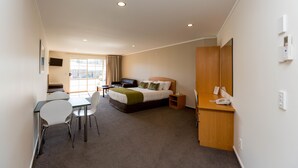 A hotel room with a bed, bedside table, chair, desk, and a window. - Aspen Court Motel Taihape (Taihape)