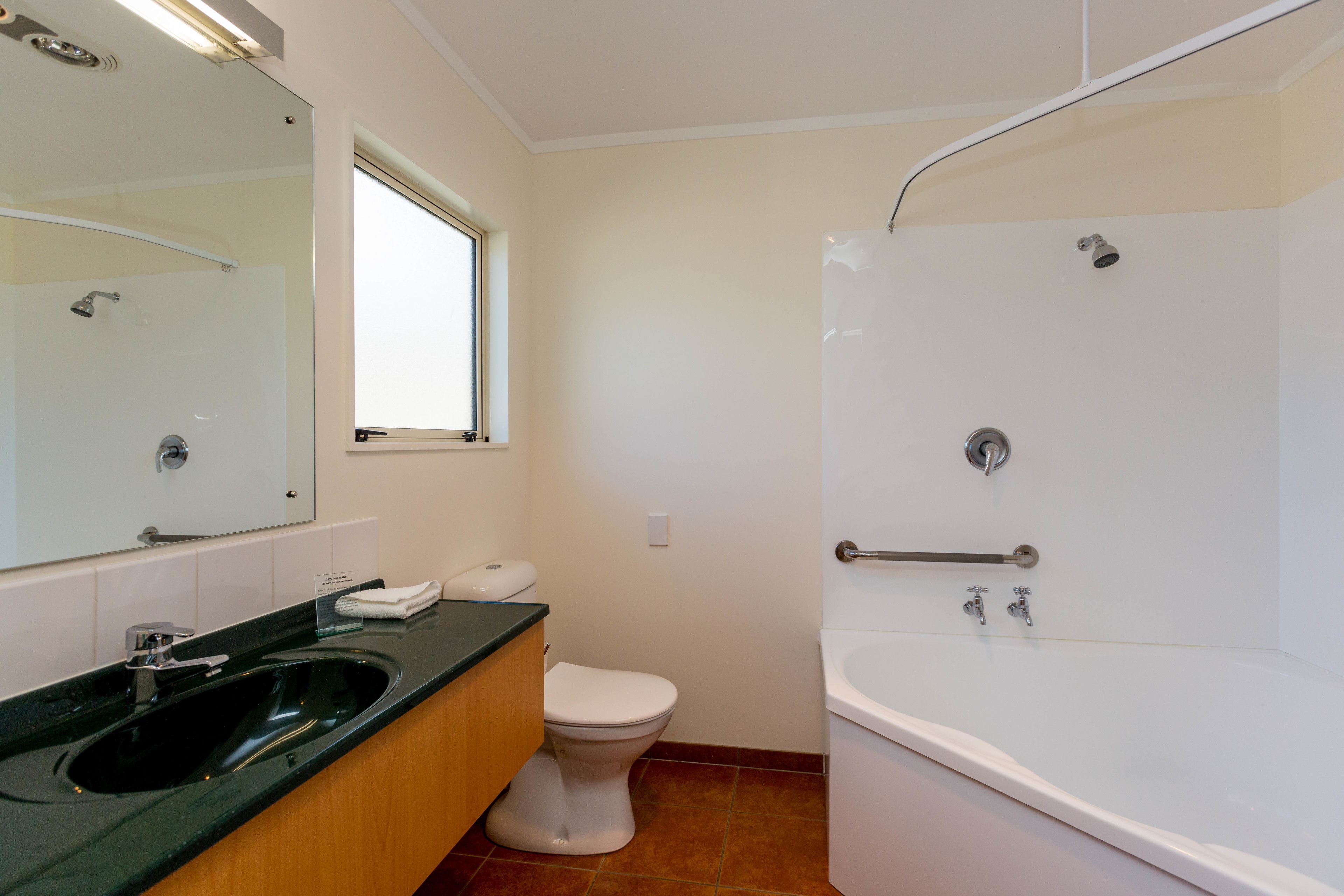 A bathroom with a black sink, white toilet, and a white bathtub.