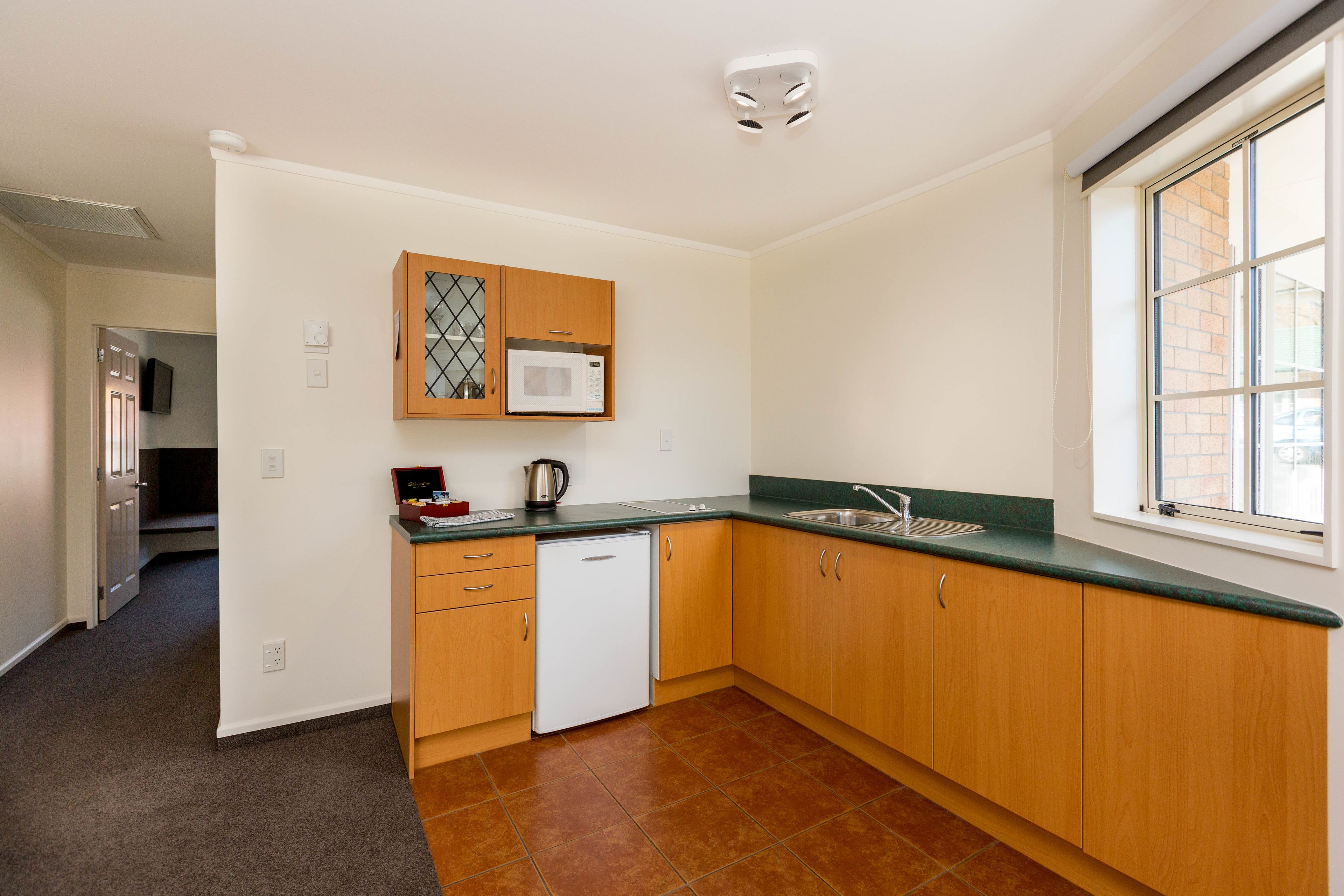 A kitchen with wooden cabinets, a microwave, a dishwasher, and a window with a view of the outside.
