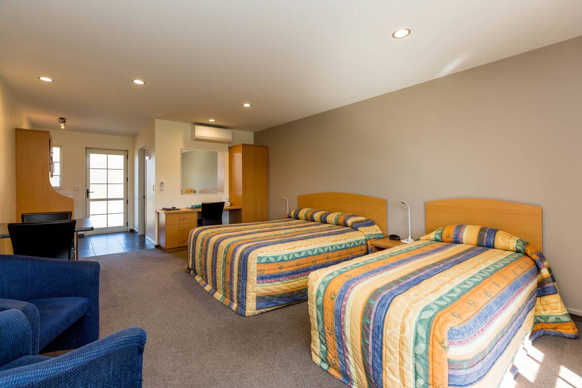 A bedroom with two beds, a desk, and a chair.