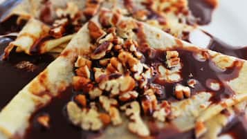 Un plato de crepas cubiertas de nueces picadas y salsa de chocolate.