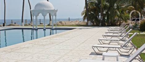Zona de piscina con sillones de descanso y un pabellón.