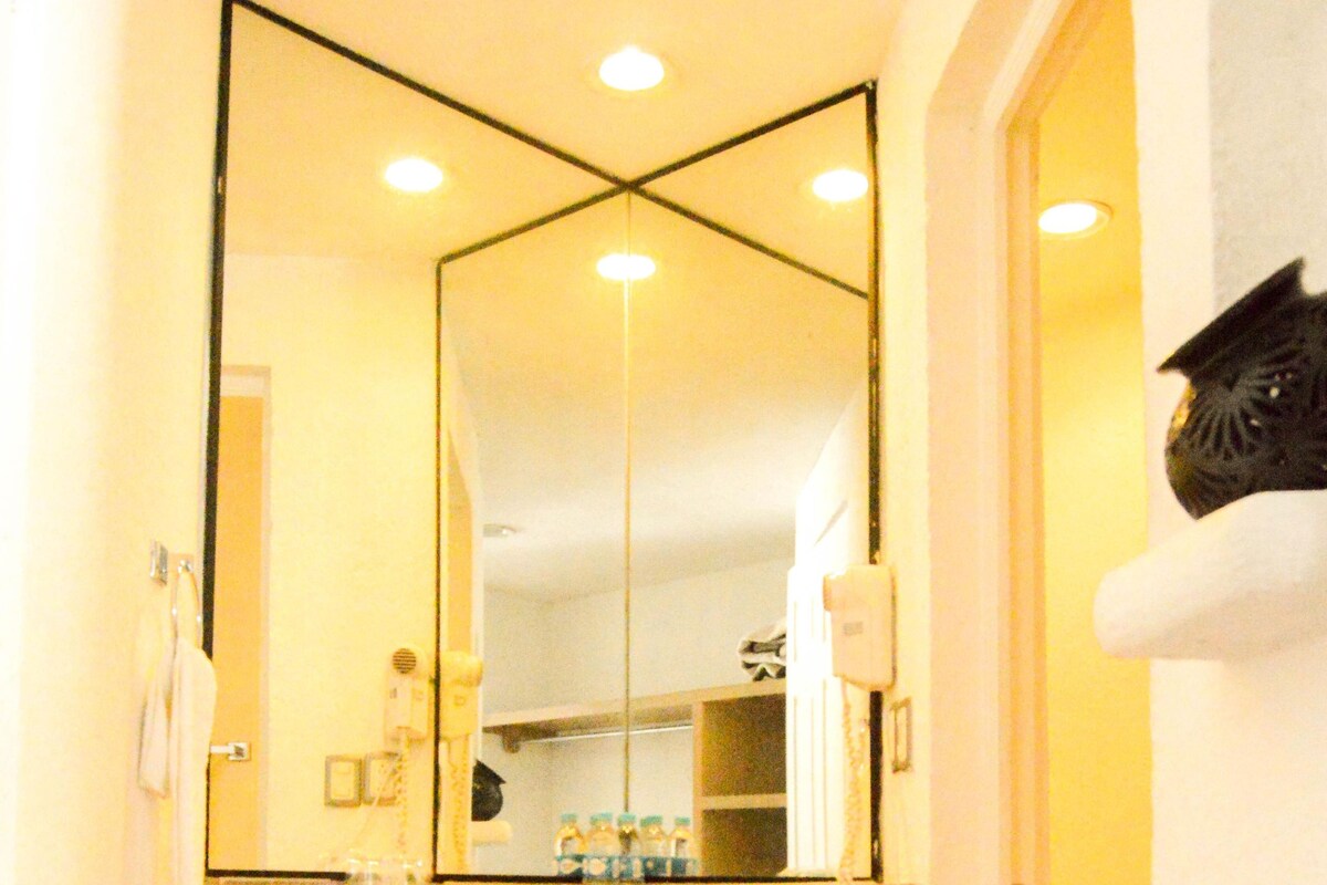 A bathroom with a large mirror, a sink, and a toilet.