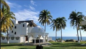 Un edificio blanco con una cúpula y arcos, rodeado de palmeras y un cielo despejado.