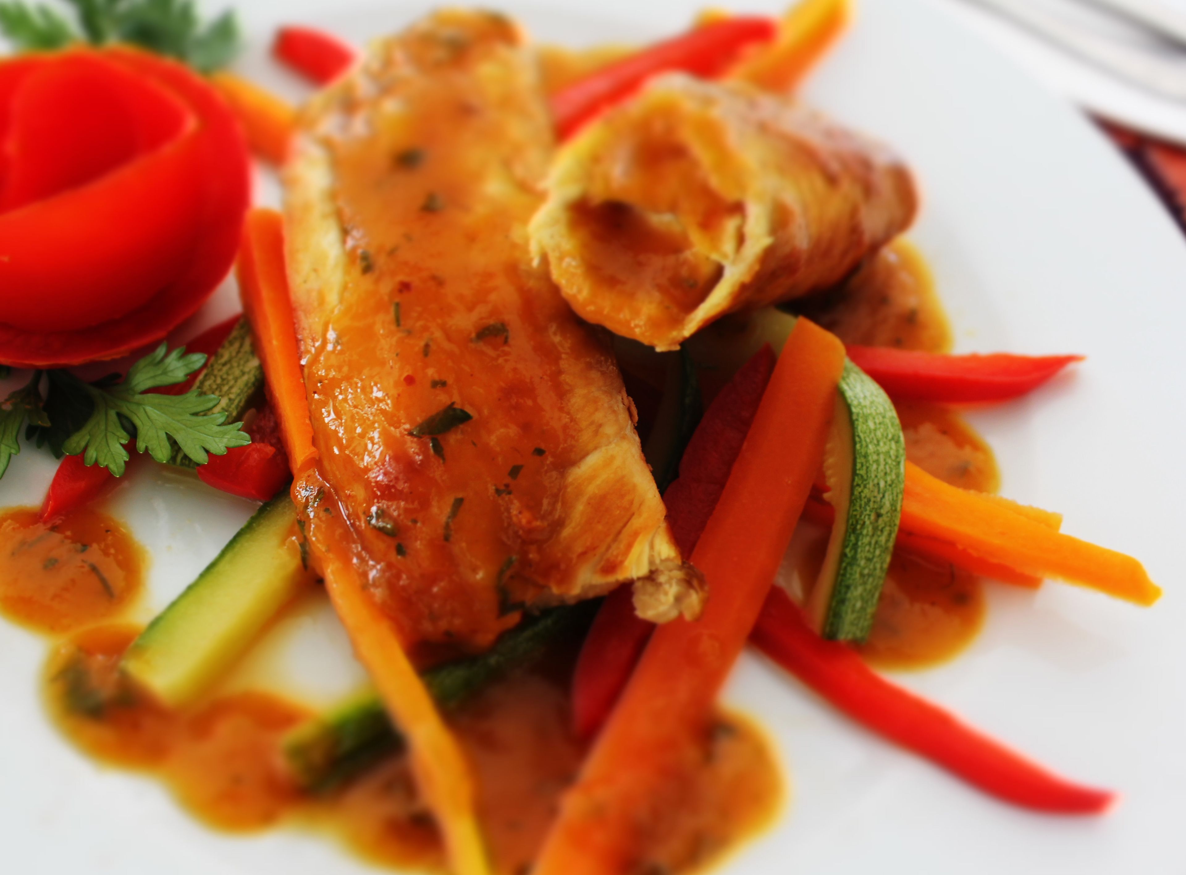 A plate of food with a piece of meat, vegetables, and a sauce.