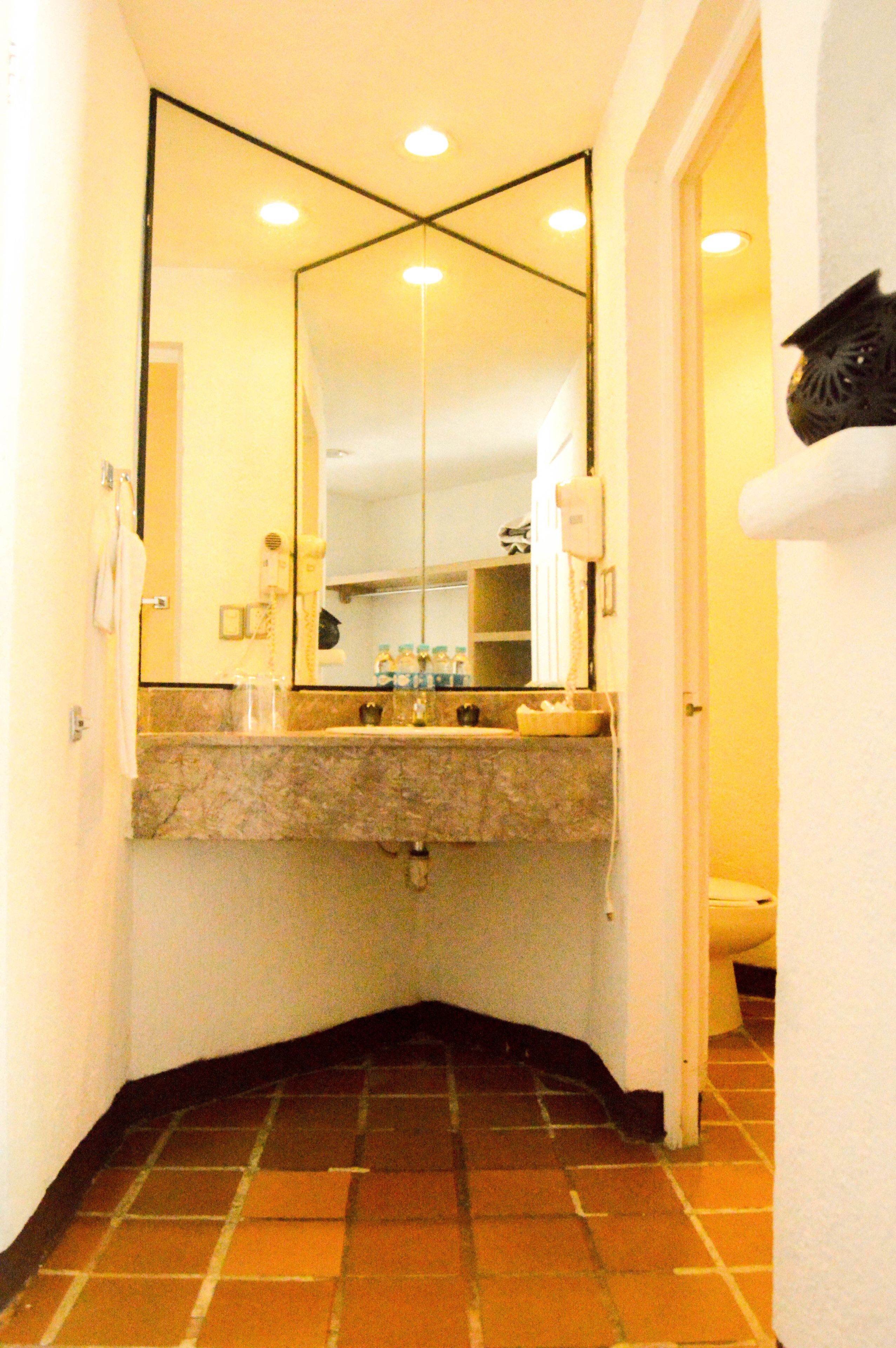 A bathroom with a mirror, sink, and toilet.