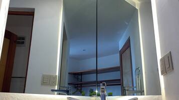 Un baño con un espejo grande, un lavabo blanco y una encimera de mármol.