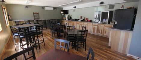 A spacious kitchen with wooden cabinets, a refrigerator, and a dining area with multiple chairs and tables.