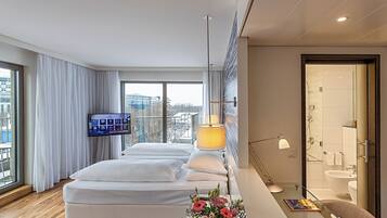 Ein modernes Hotelzimmer mit einem großen Bett, einem Fernseher, einem Balkon mit Blick und einem separaten Badezimmer.