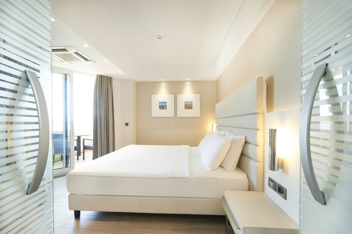 Deluxe Room, Balcony, Partial Sea View | Minibar, in-room safe, desk, blackout drapes