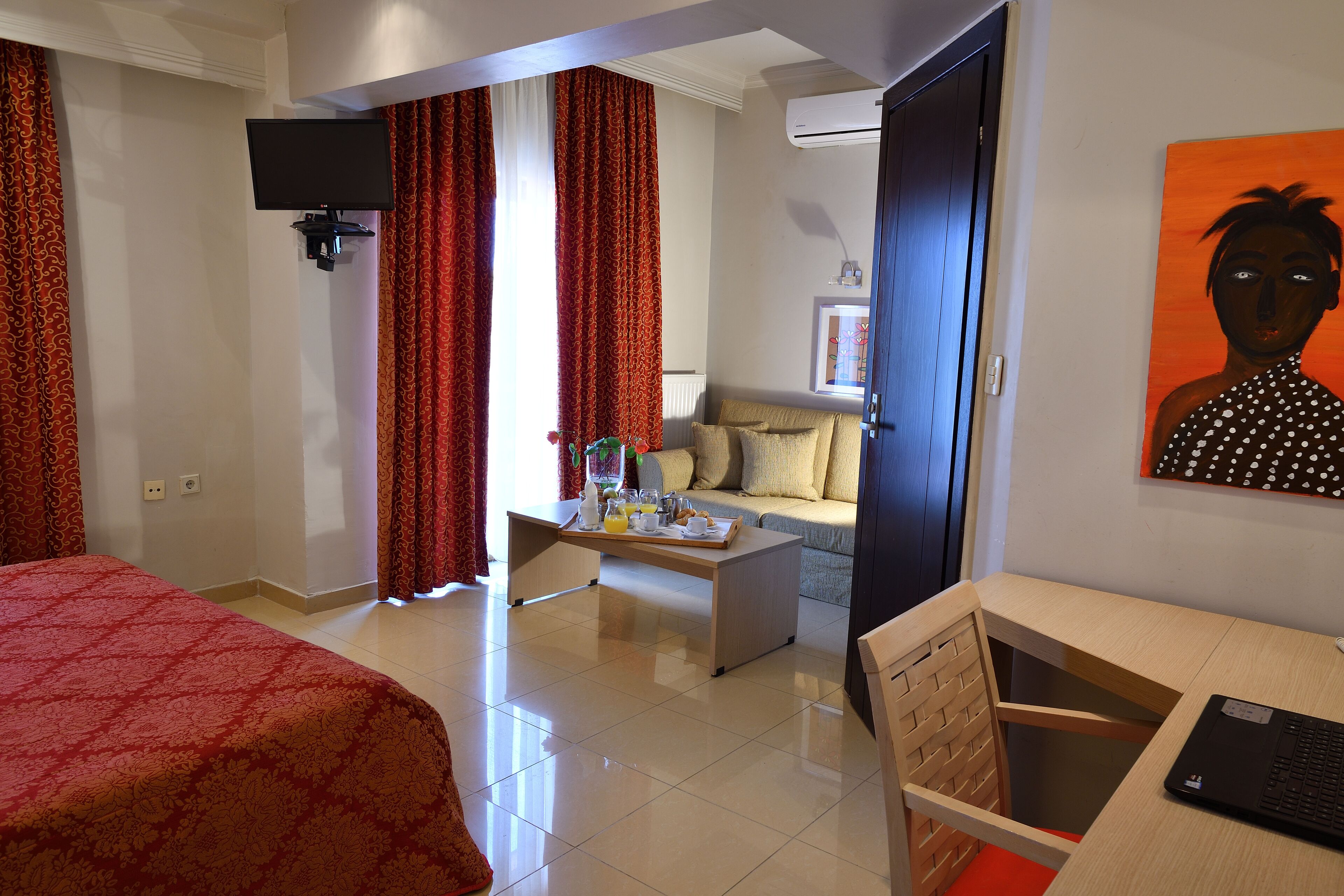 A hotel room with a bed, a desk, a chair, a coffee table, and a TV.