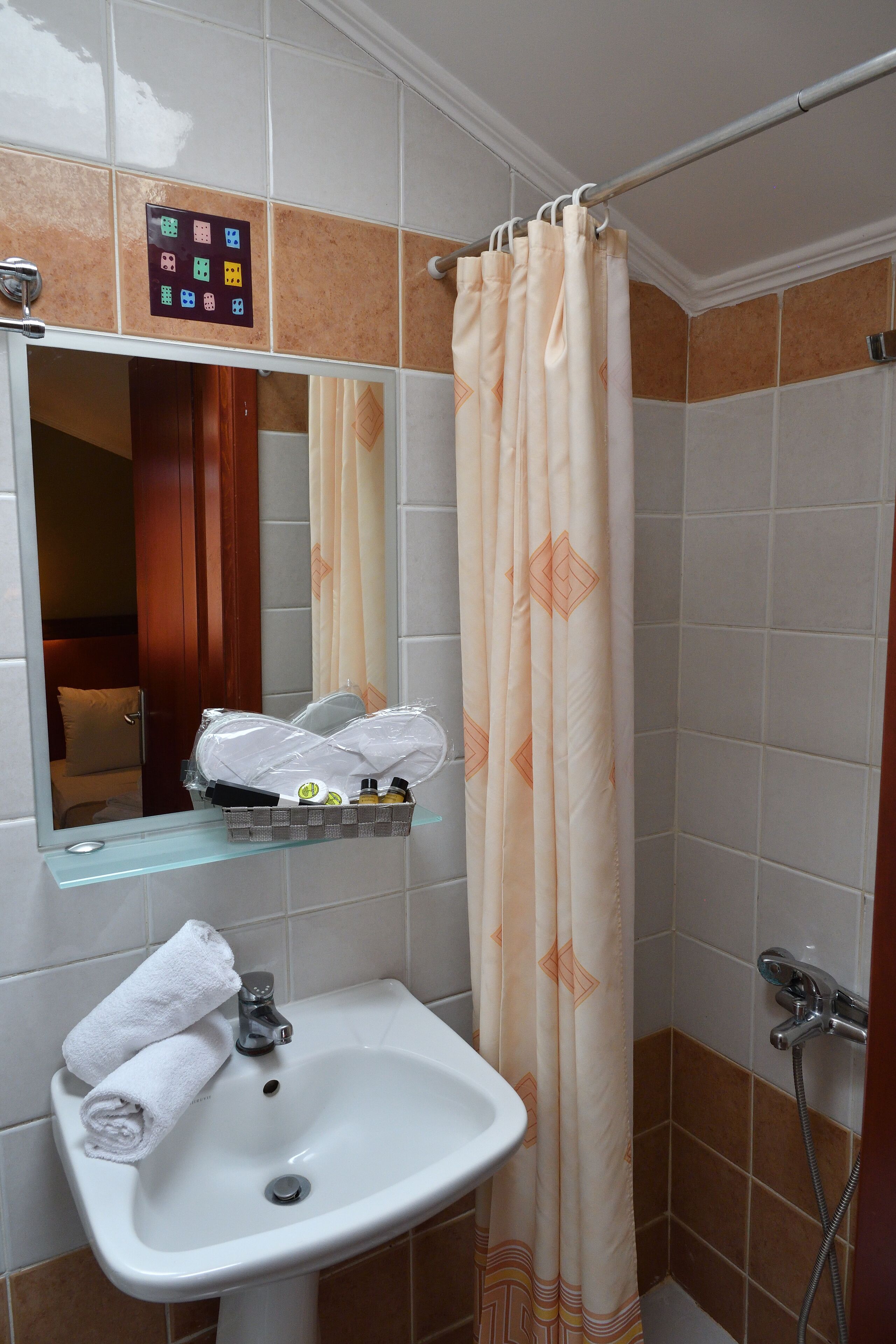 Un baño con lavamanos, espejo y cortina de ducha.
