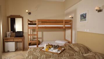 A bunk bed with a tray of breakfast items, a desk with a laptop, and a refrigerator.