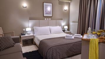 Ein Hotelzimmer mit Bett, Nachttischen, Schreibtisch, Stuhl, Heizkörper und Vorhängen.