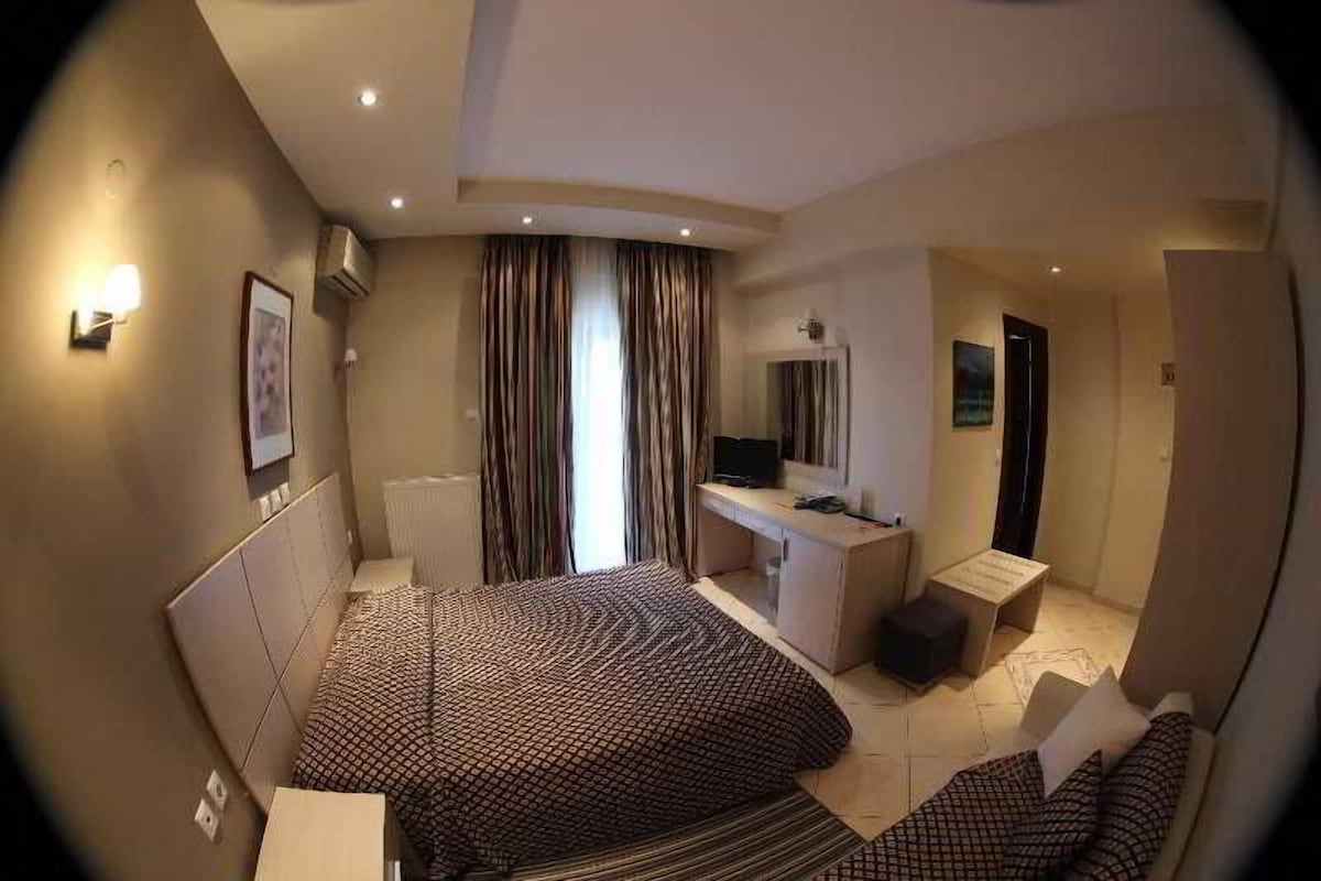 A hotel room with a bed, a desk, a chair, a TV, and a bathroom.