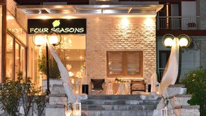 Hotellin sisäänkäynti, jossa on kivinen julkisivu, portaikko, joka johtaa sisäänkäynnille, ja kyltti, jossa lukee ”FOUR SEASONS”.