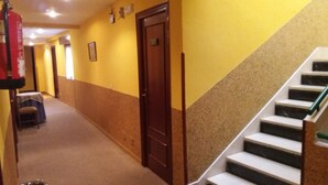 A hallway with a staircase, a door, and a small table with a chair. - Pension Monteverde (Cangas de Onis)
