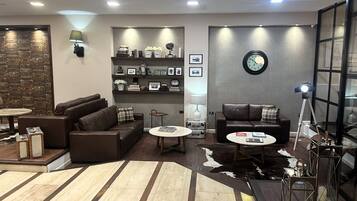 A modern living room with leather sofas, a round coffee table, and a bookshelf with various items.