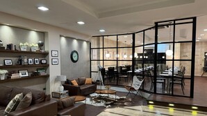 A modern living room with a sofa, a coffee table, and a dining area visible through a glass partition. - Alvear Hotel (Montevideo)