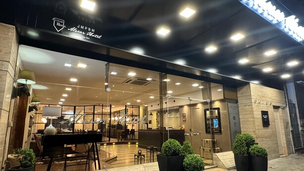 The exterior of the Alvear Hotel with a modern design, featuring a glass facade, outdoor seating area, and potted plants. - Alvear Hotel (Montevideo)