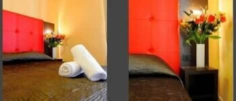 A hotel room with a bed, a nightstand, a vase with flowers, and a red headboard.