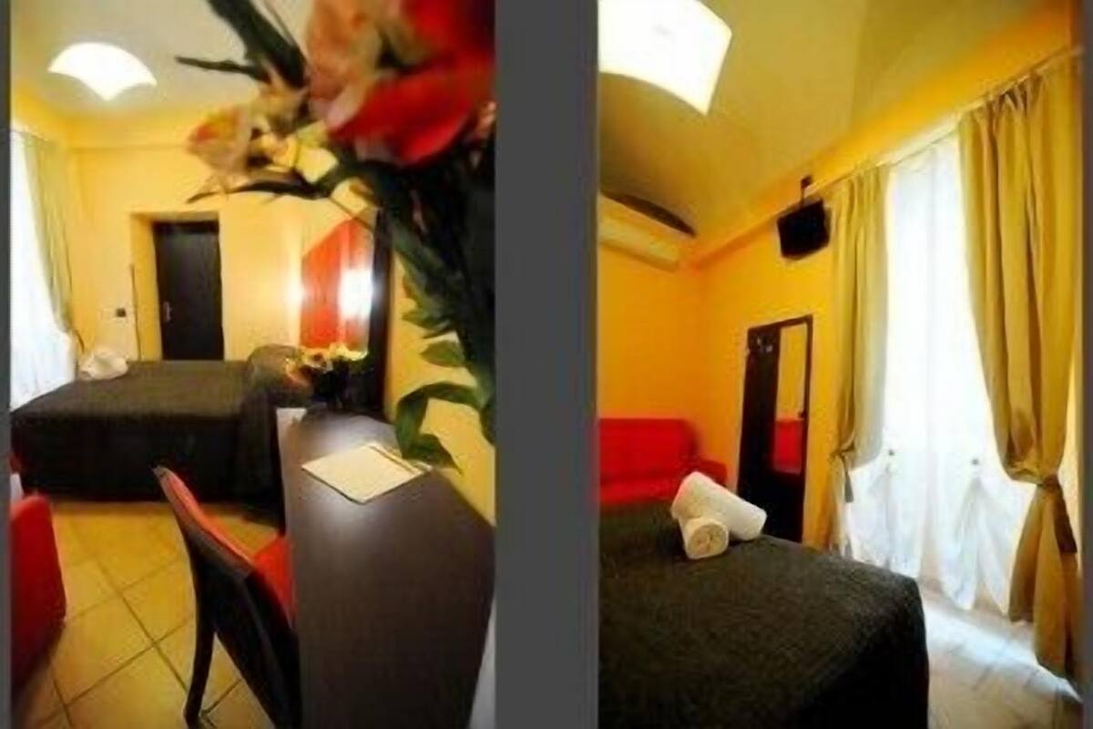 A hotel room with a bed, a desk, and a chair. There is a window with curtains.