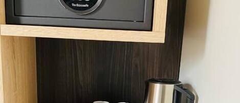 Un mini-bar compact comprenant une machine à café, deux tasses et un petit réfrigérateur.