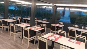An indoor dining area with tables and chairs, large windows, and a view of the outdoors. - Hôtel Martinez Grenay (Grenay)