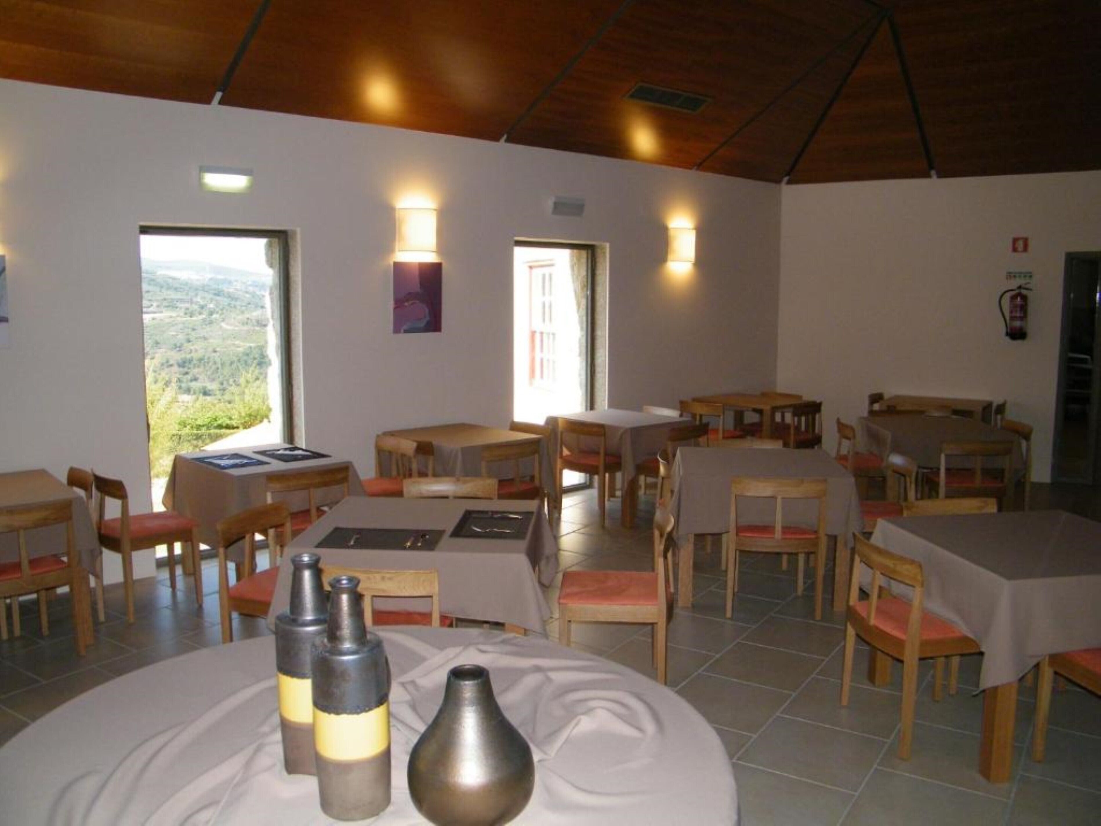 Un espace repas avec des tables et des chaises, une vue par la fenêtre et un extincteur fixé au mur.