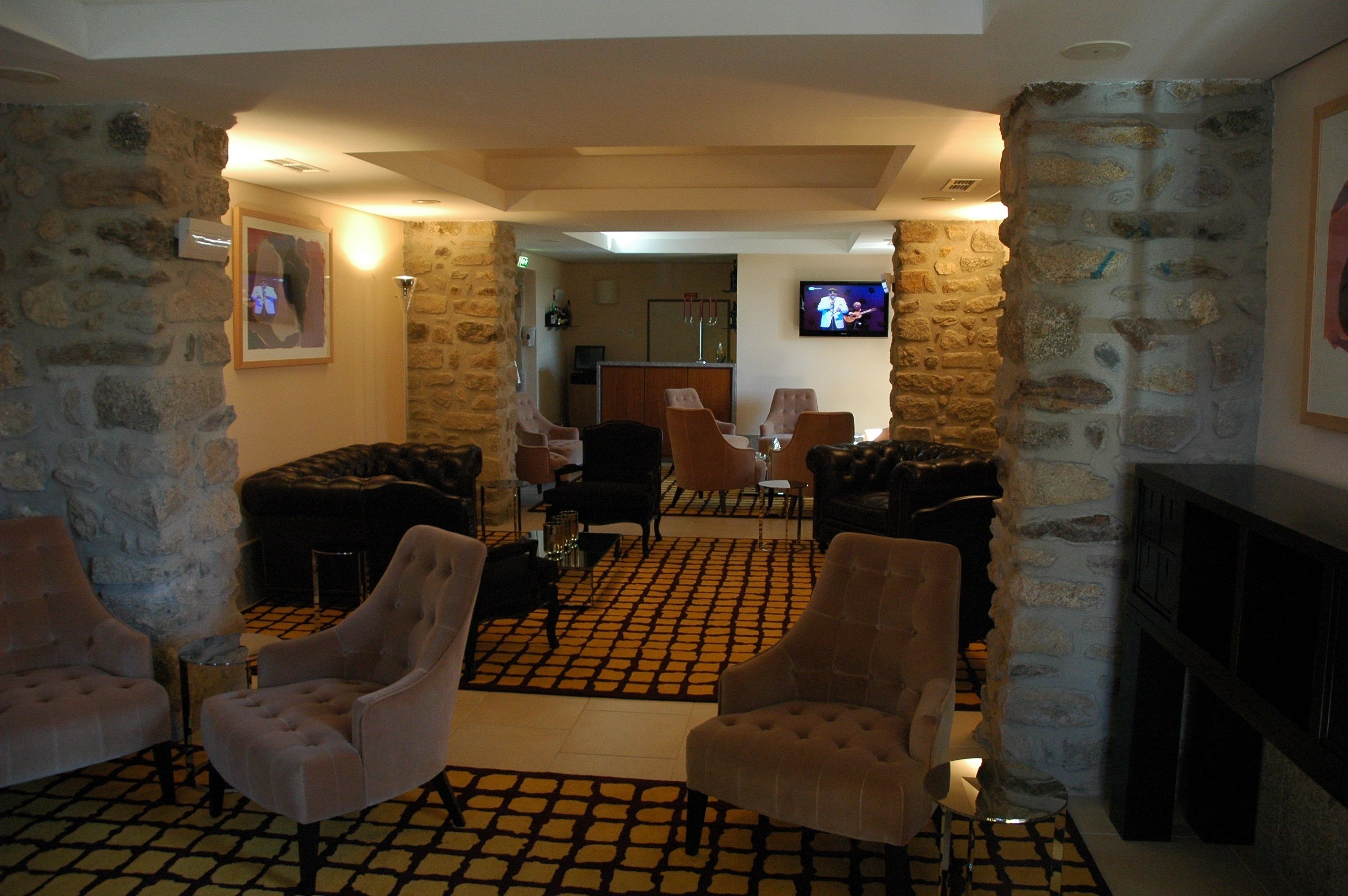 A lobby with stone walls, a checkered floor, and seating areas with armchairs and sofas.