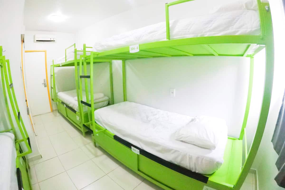 Une chambre de dortoir avec des lits superposés, une porte et un appareil de climatisation.