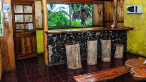 Eine Bar mit Holzboden, einer Steinwand, Holzstühlen und einer Bank.