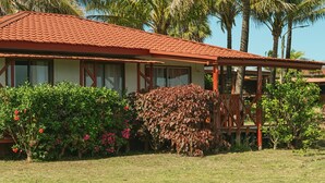Ein Haus mit rotem Ziegeldach, umgeben von üppiger Vegetation und Palmen.