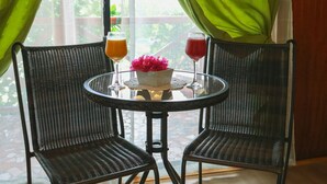 Ein Zimmer mit zwei Korbstühlen um einen kleinen runden Tisch, mit Orangensaft und einem roten Getränk in Gläsern.