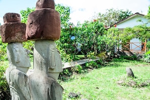 A stone statue in a garden with a house in the background.