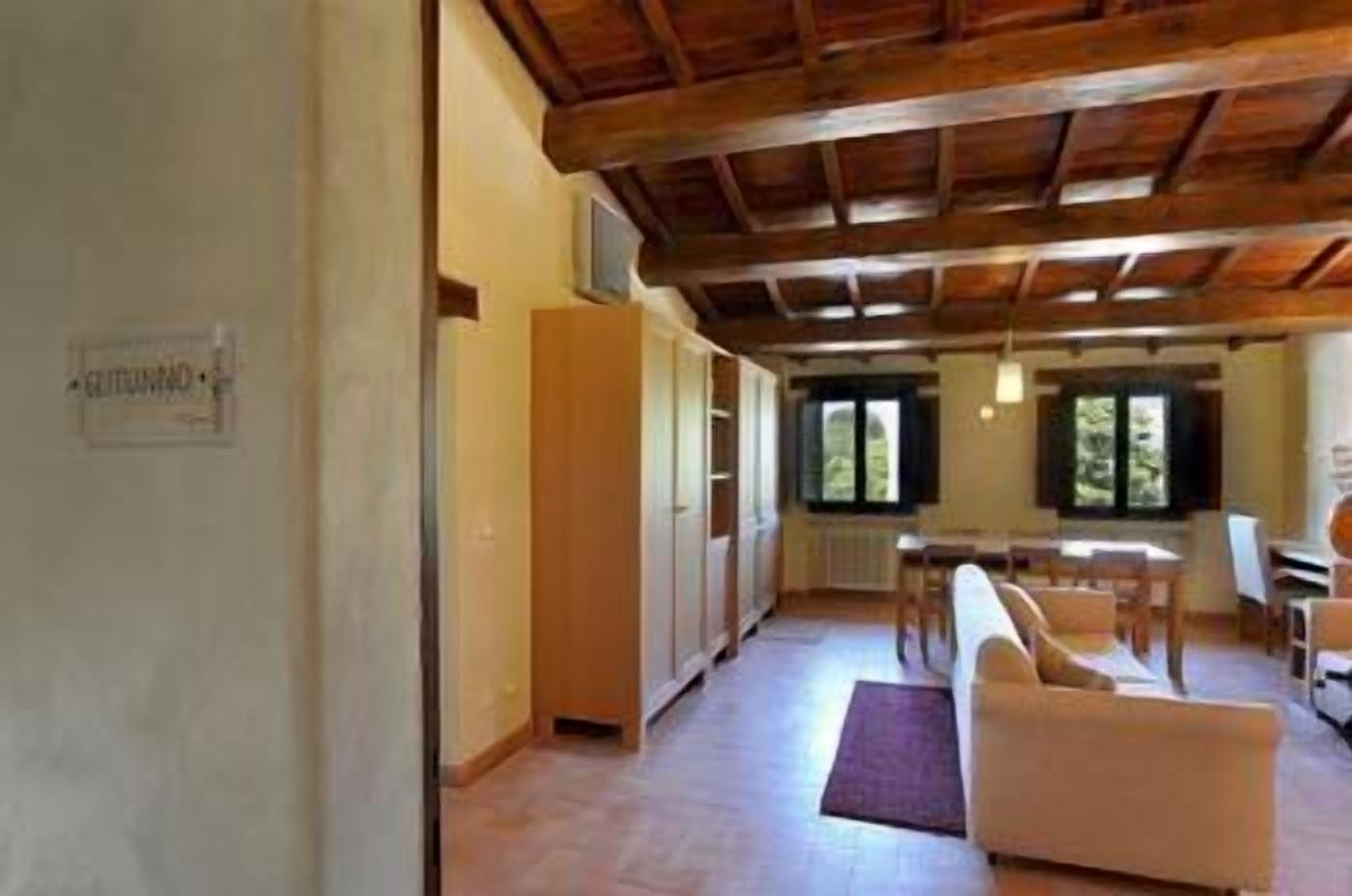 A spacious room with a wooden ceiling, a dining area with a table and chairs, and a sofa.