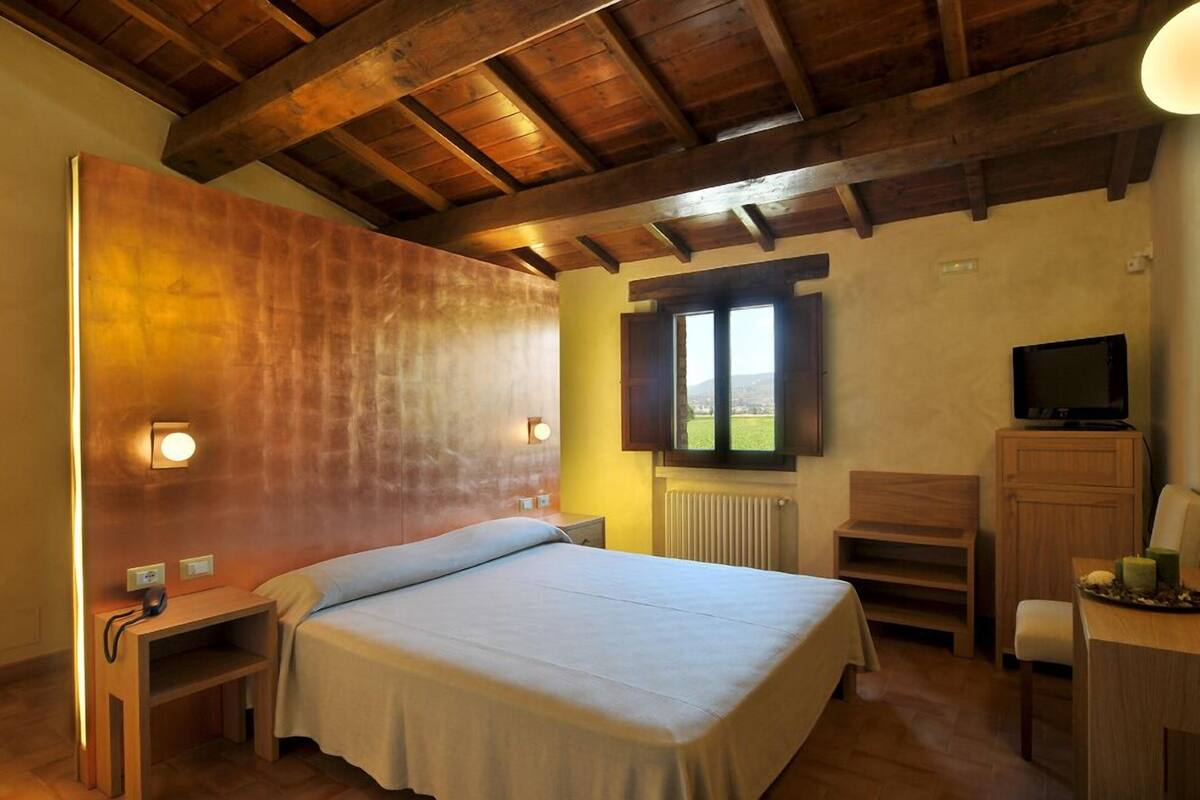 Ein Schlafzimmer mit Holzboden, einem Bett, einem Fernseher, einem Schreibtisch und einem Fenster mit Blick.