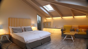 Un dormitorio con cama, sofá y tragaluz.