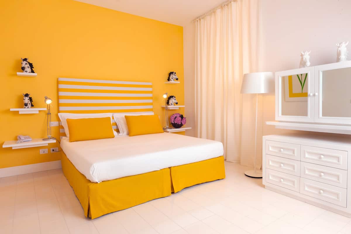 Une chambre à coucher comprenant un lit, une table de chevet, une lampe, une commode et des objets décoratifs.