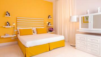 A bedroom with a bed, a nightstand, a lamp, a dresser, and decorative items.