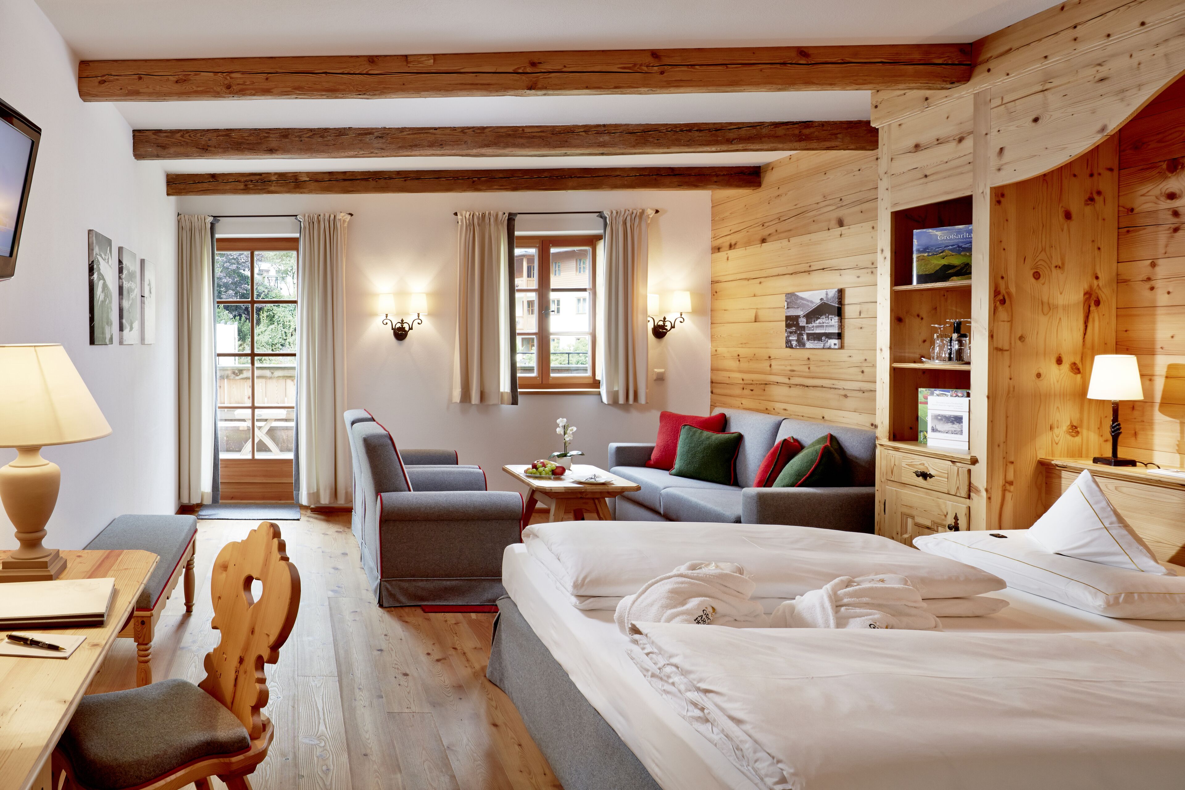 Habitación de hotel con techo de madera, una cama, un sofá, un escritorio y una silla.