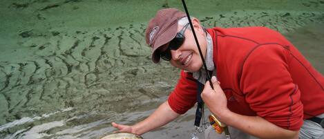 A person holding a fish near a body of water.