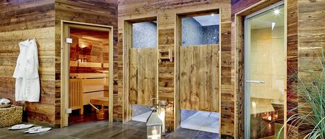 A modern bathroom with wooden walls, a glass shower enclosure, and a lantern on the floor.