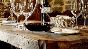 Une table en bois rustique, ornée de verres à vin, d’une bouteille de vin et d’un chandelier.