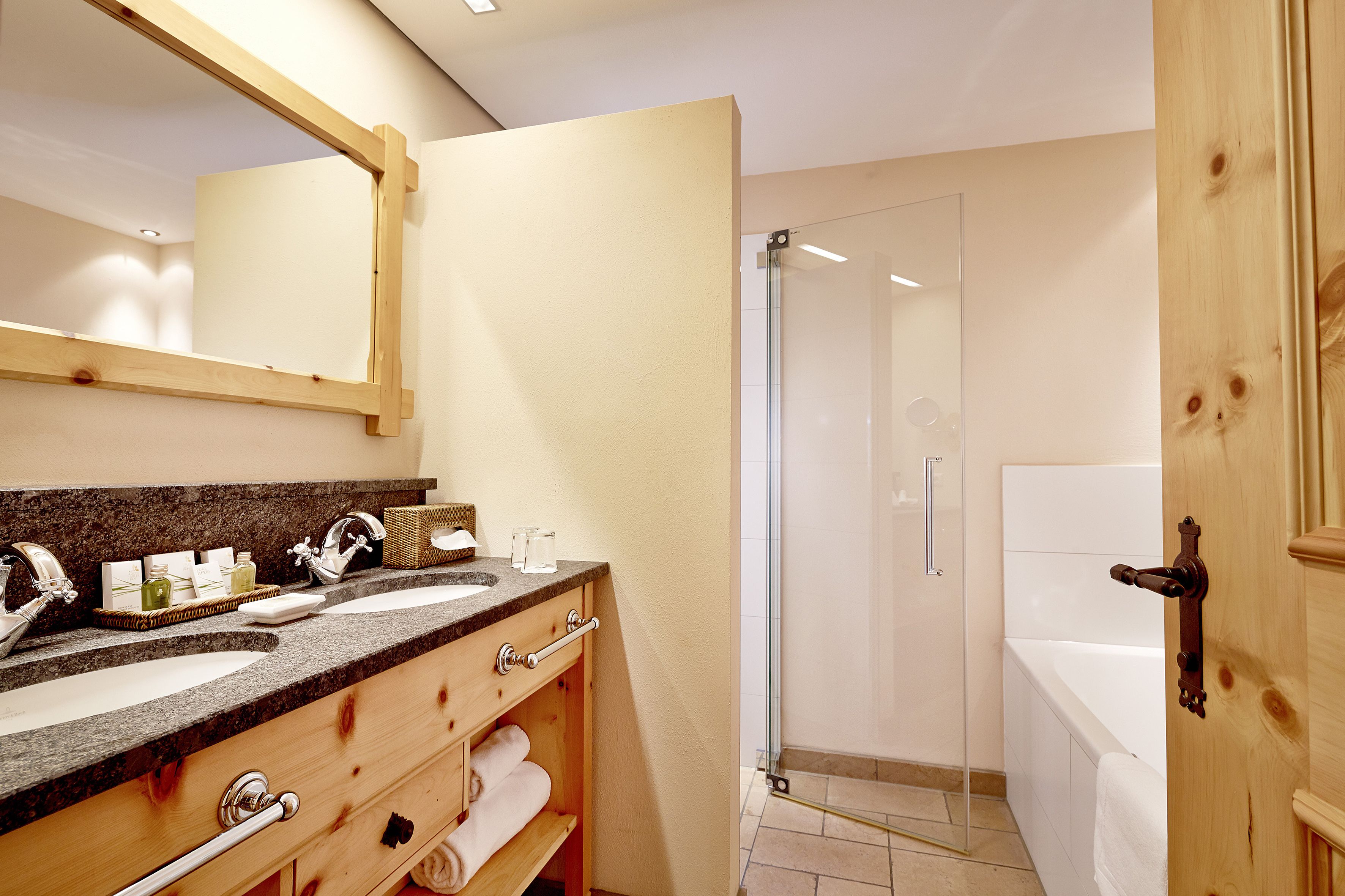 A bathroom with two sinks, a mirror, a shower, and a bathtub.