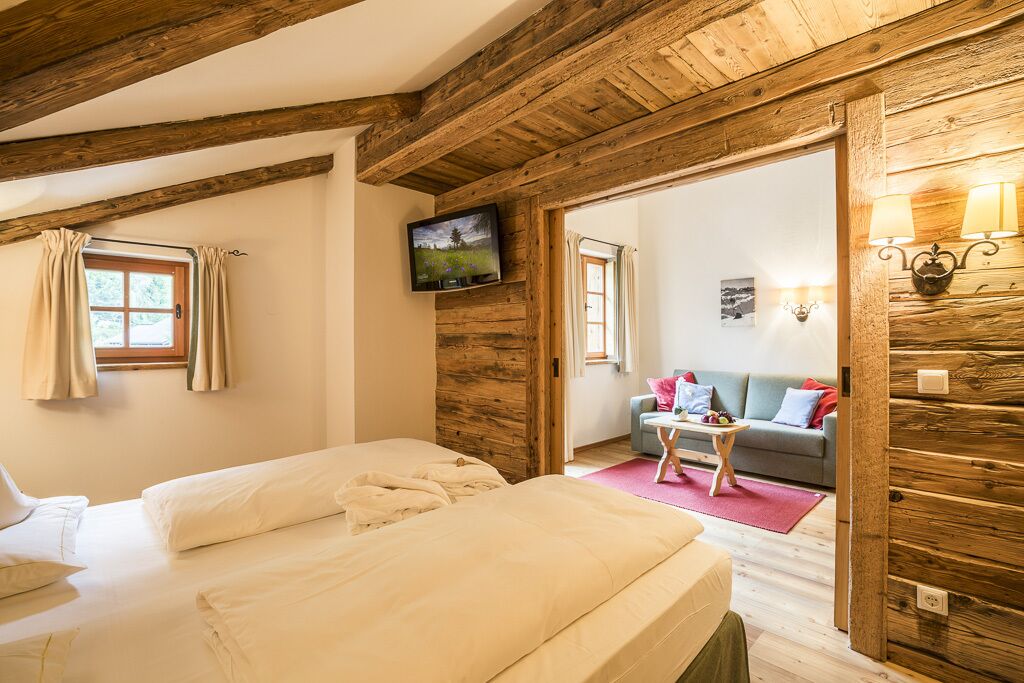 Una habitación acogedora con techo de madera, una cama, un televisor y un sofá con una mesita.