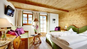 Um quarto com painéis de madeira, uma cama, uma escrivaninha, uma cadeira, uma televisão e uma janela com cortinas.
