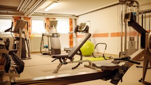 A gym with exercise equipment, a treadmill, and a green exercise ball.